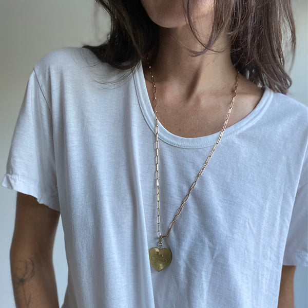 Load image into Gallery viewer, Girl with Brown Hair wearing white t shirt and heart gold colored charm necklace
