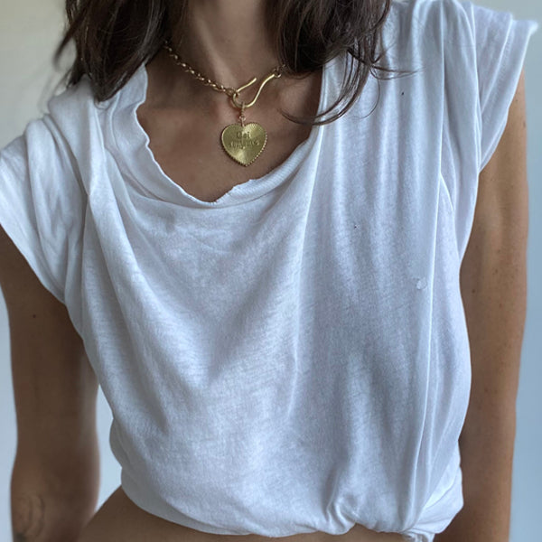 Woman with brown hair wearing a white t shirt and gold colored Necklace with Heart Charm